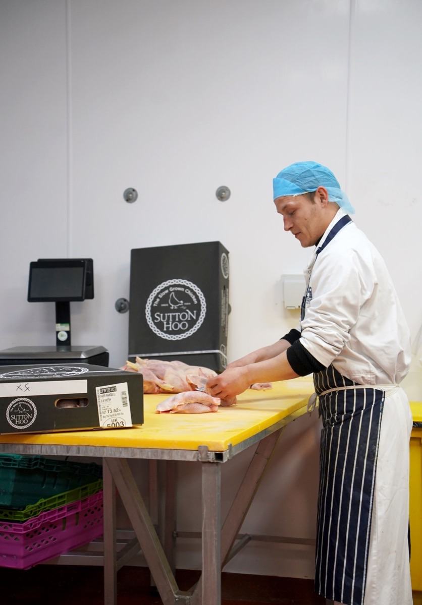 A Bodiam Foods butcher portioning whole chicken in the cutting room