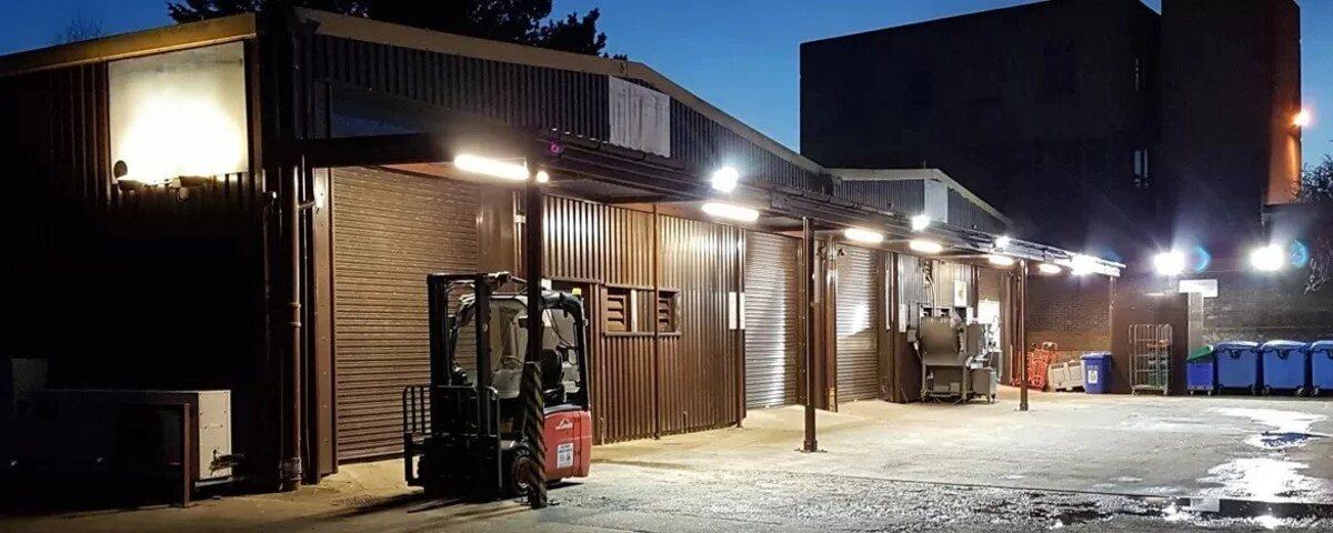 The Bodiam Foods depot at night, vans loaded under the lights before the morning round